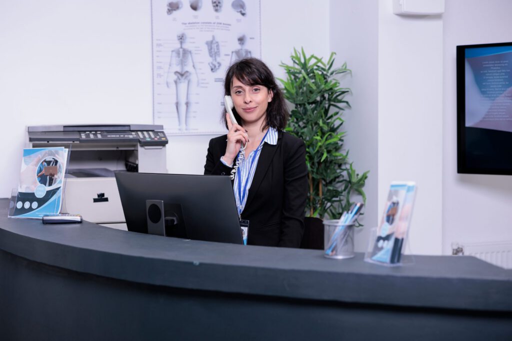 Secrétaire médicale prenant un rendez-vous au téléphone à l’accueil d’un cabinet